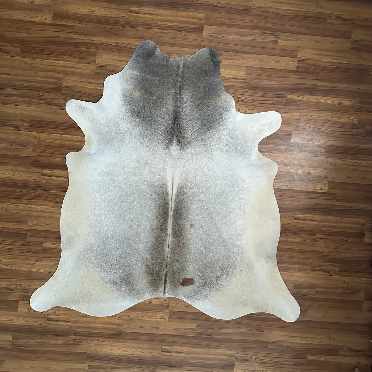 Grey cowhide rug, full overhead view — Large irregular grey and white patches with darker grey markings over cream base