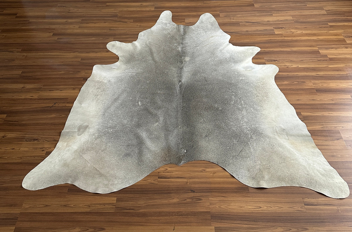 Grey cowhide rug, full overhead view — Large irregular light grey patches with darker grey undertones over cream base