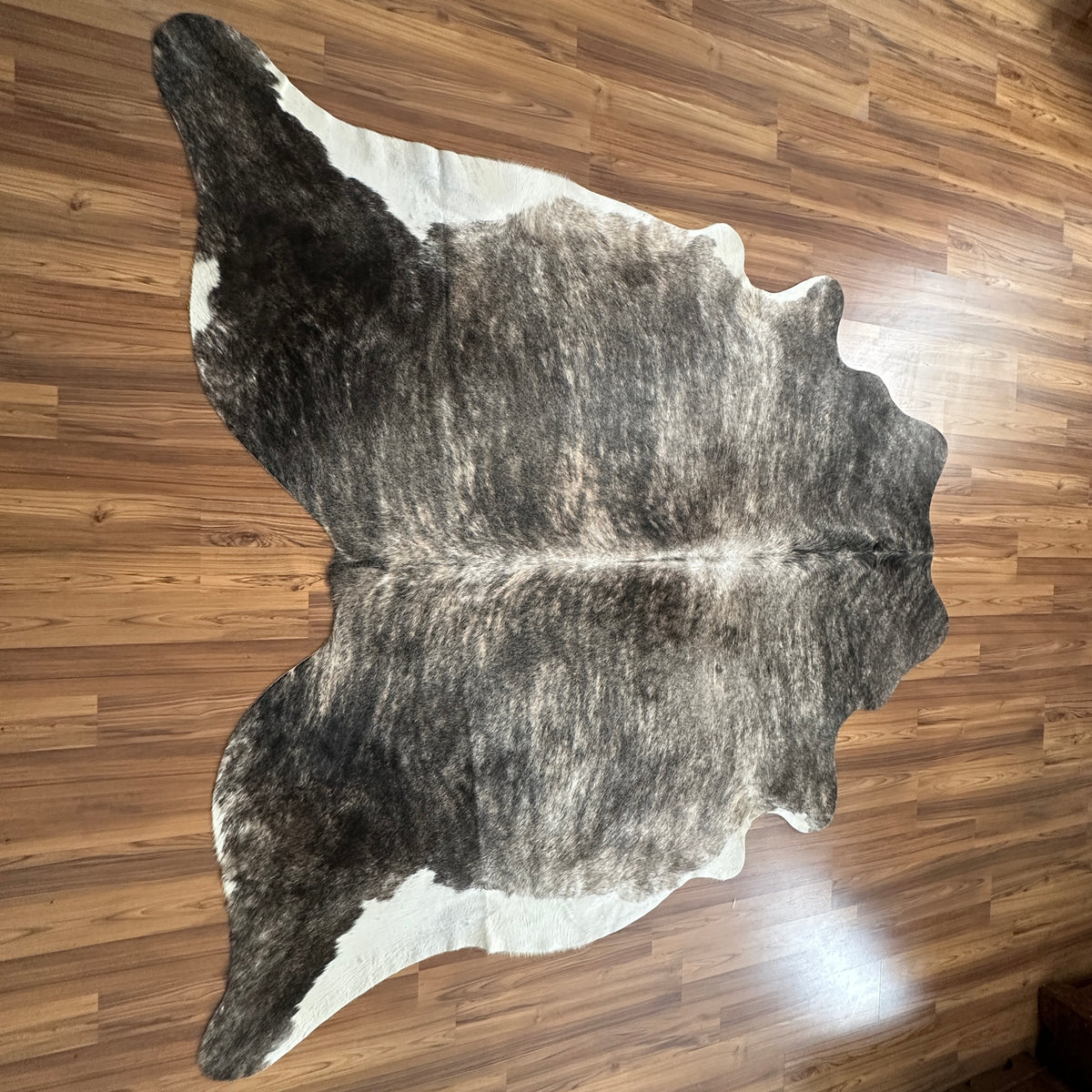 Grey cowhide rug, full overhead view — Large irregular dark grey and charcoal patches with cream and white accents over light