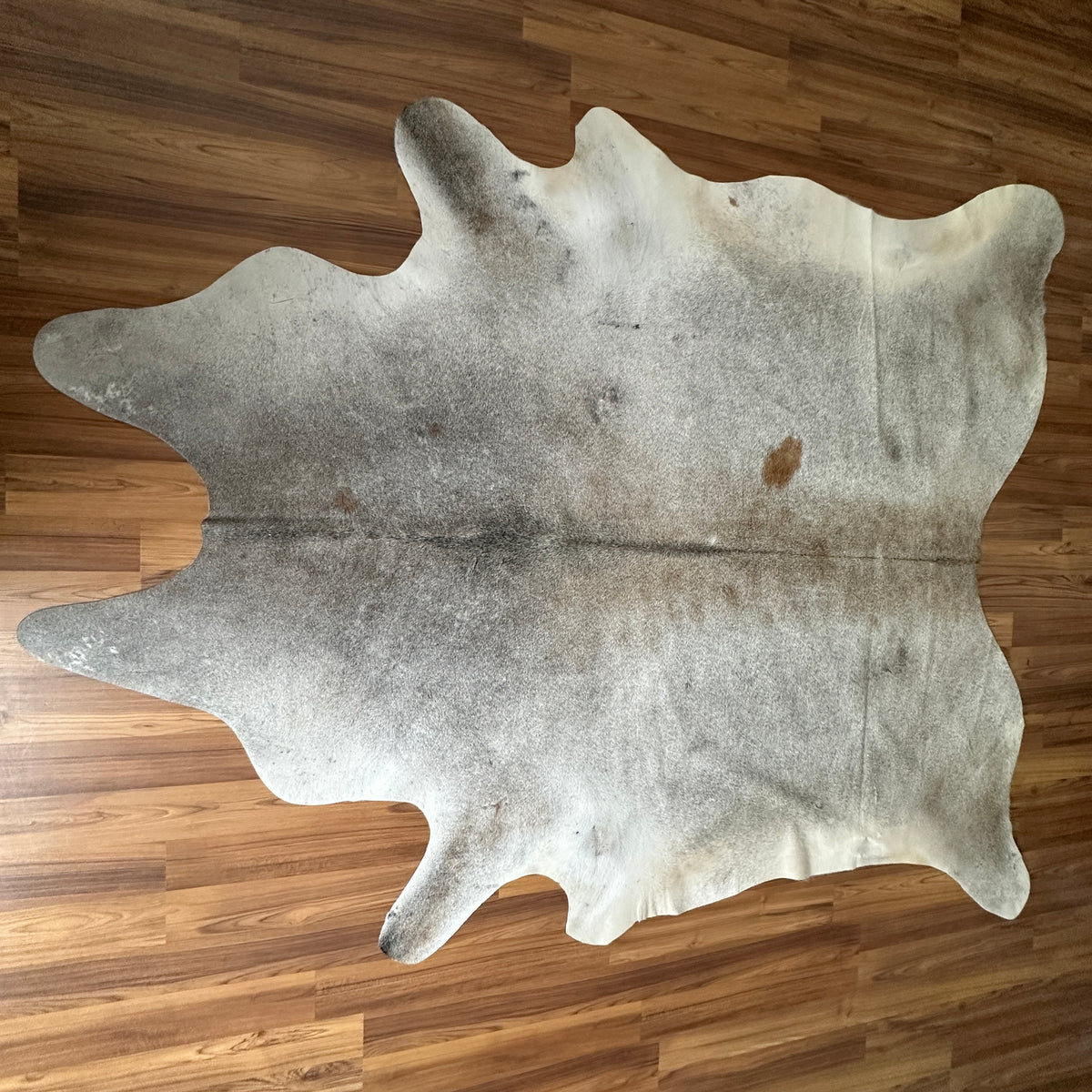 Grey cowhide rug, full overhead view — Large irregular grey and cream patches with natural mottling and subtle tan undertones