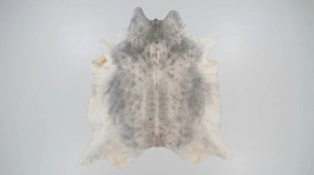 Grey cowhide rug flat lay on white background showing full hide shape
