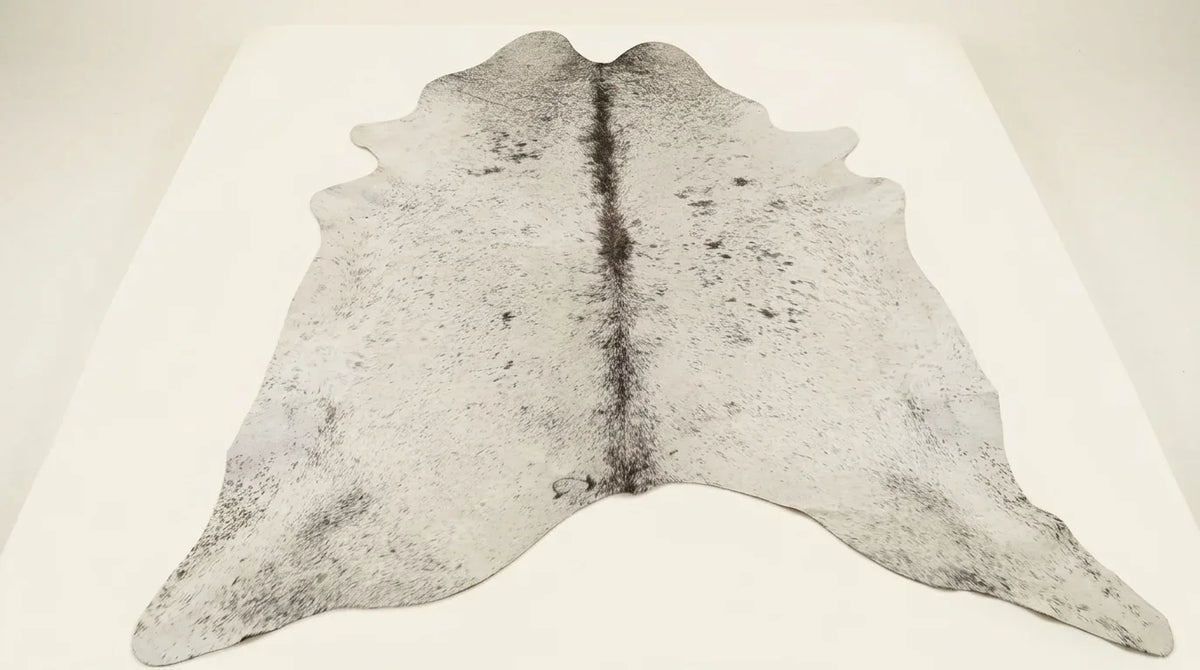 Grey cowhide rug flat lay on white background showing full hide shape