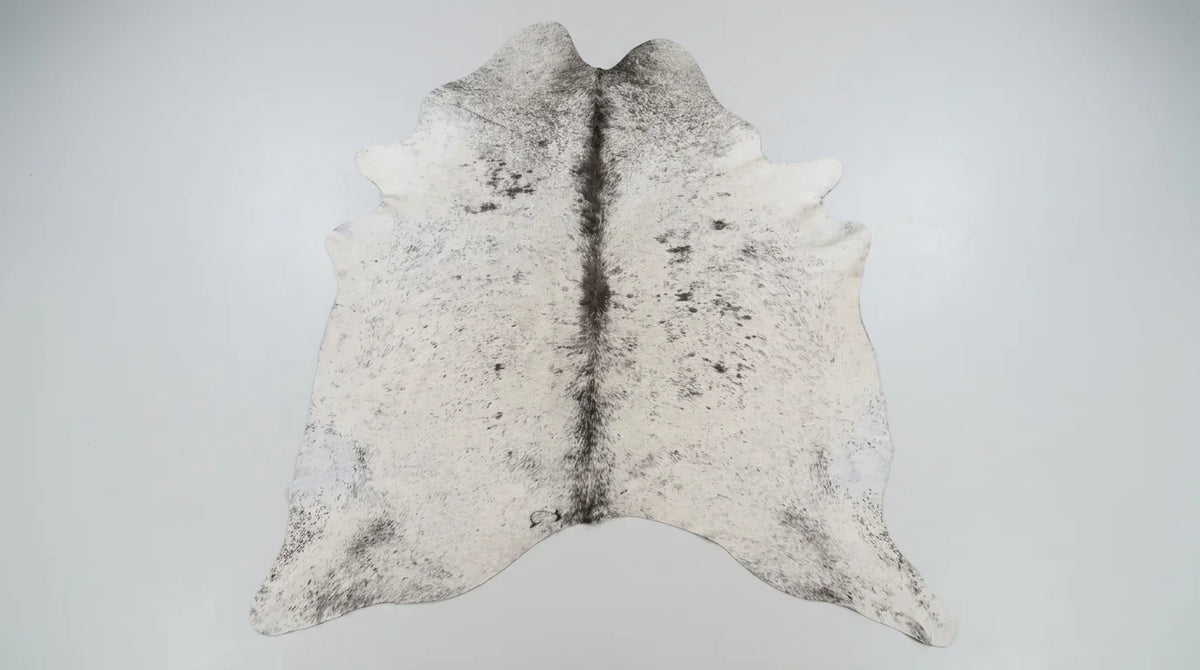 Grey cowhide rug flat lay on white background showing full hide shape