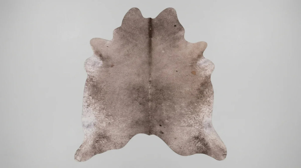 Grey cowhide rug flat lay on white background showing full hide shape