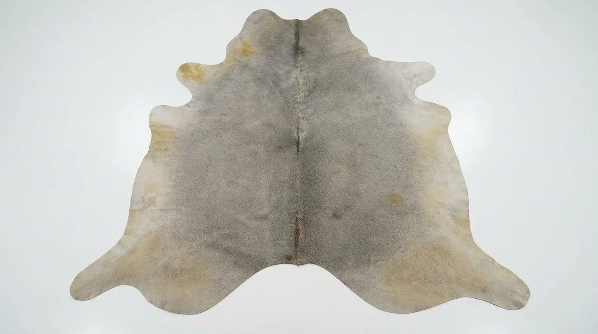 Grey cowhide rug flat lay on white background showing full hide shape