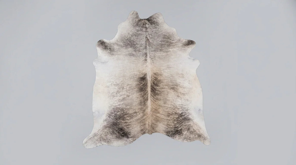Grey cowhide rug flat lay on white background showing full hide shape
