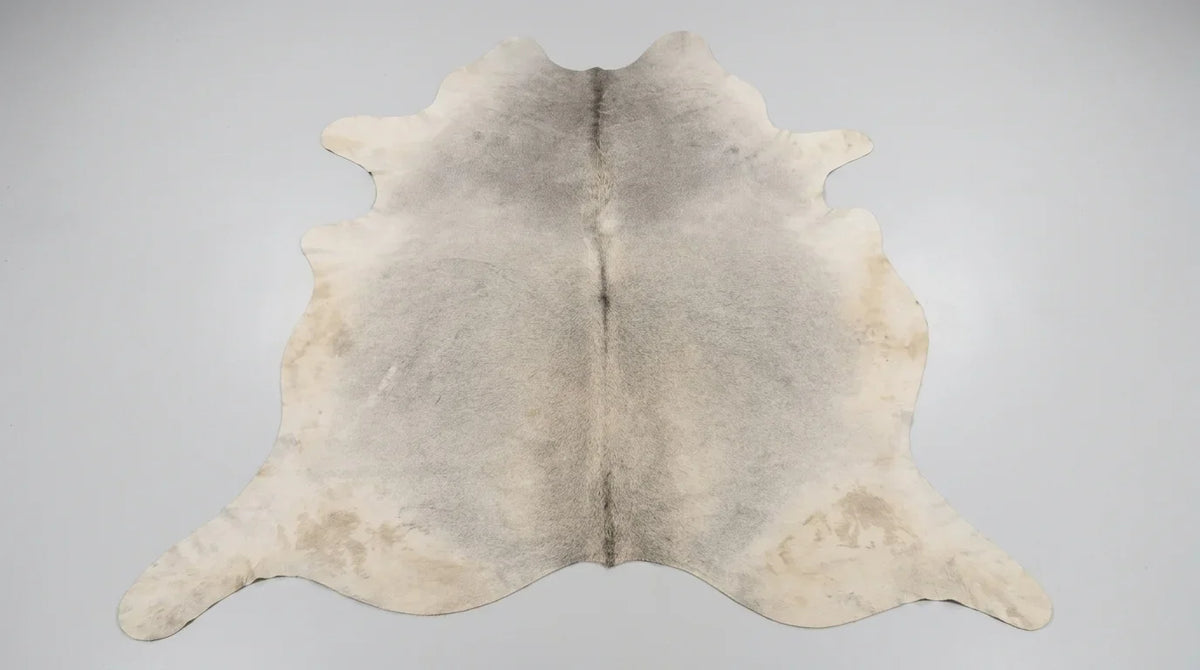 Grey cowhide rug flat lay on white background showing full hide shape