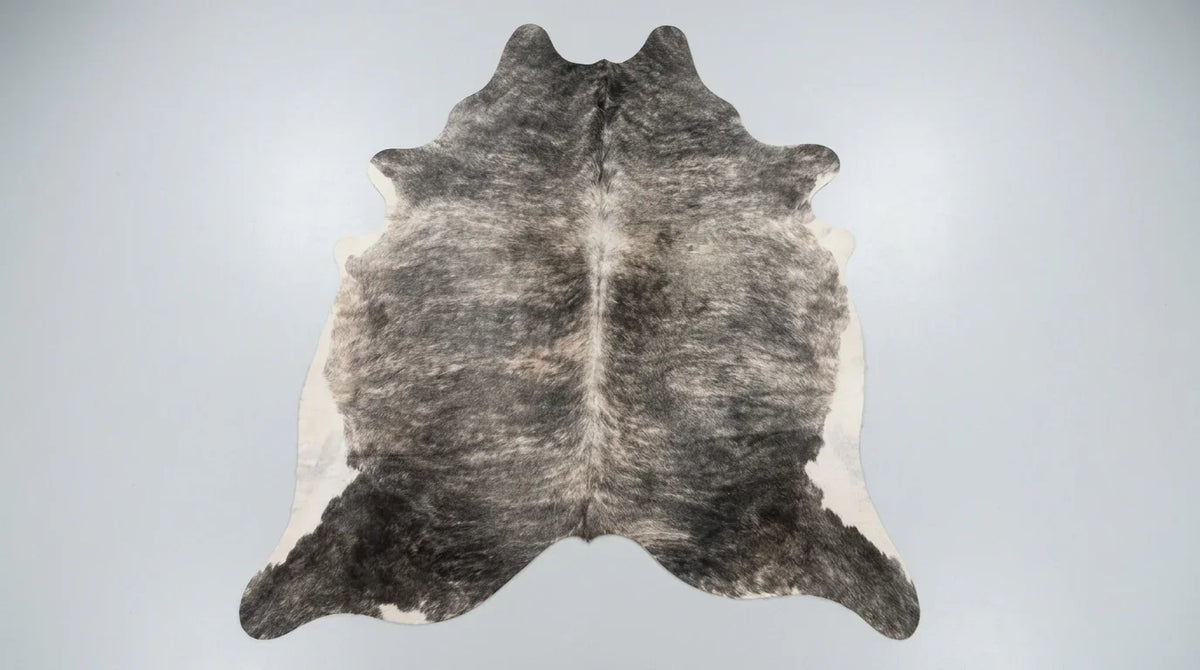 Grey cowhide rug flat lay on white background showing full hide shape