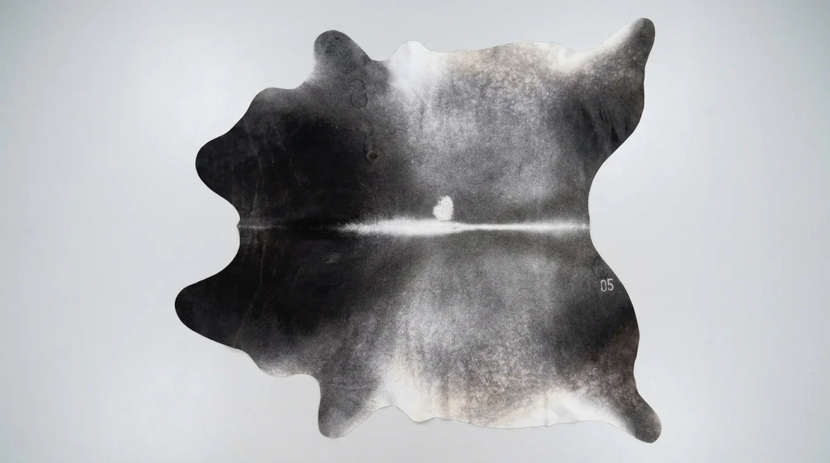 Grey cowhide rug flat lay on white background showing full hide shape