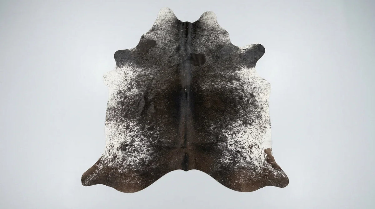 Grey cowhide rug flat lay on white background showing full hide shape
