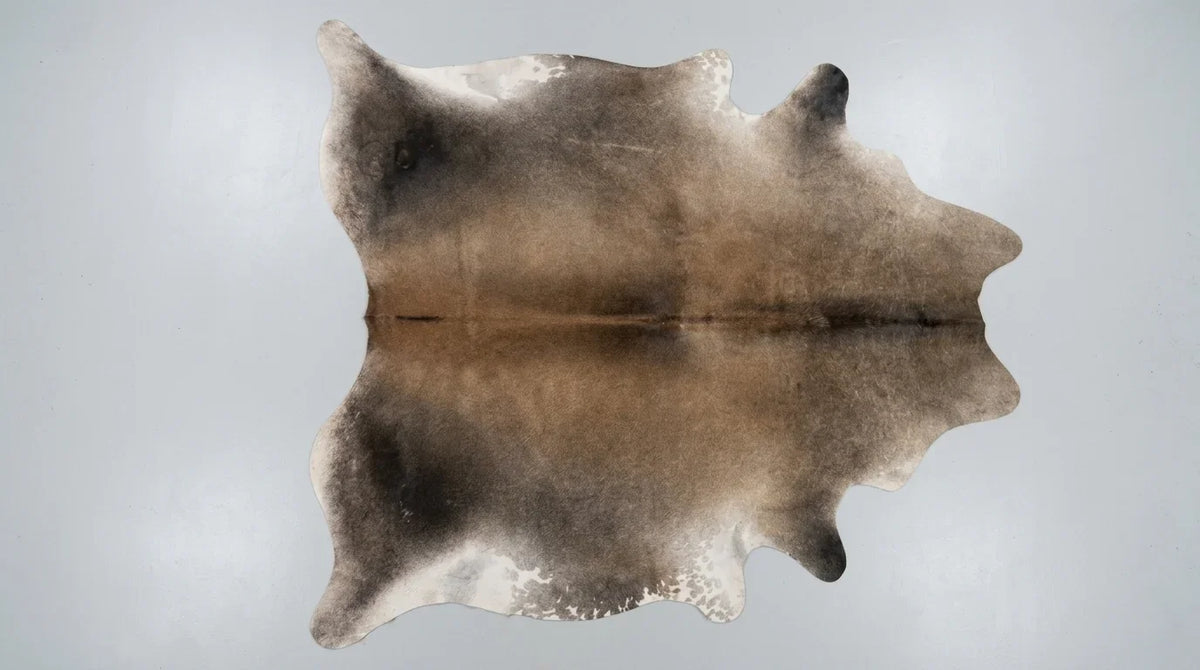 Grey cowhide rug flat lay on white background showing full hide shape