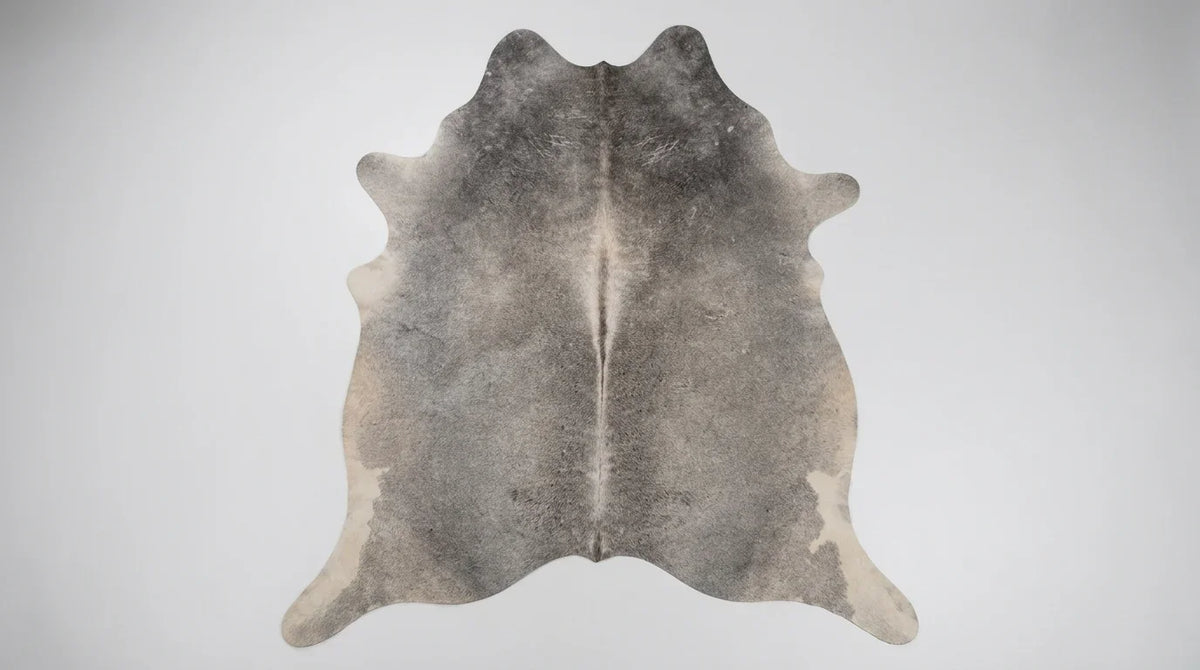 Grey cowhide rug flat lay on white background showing full hide shape