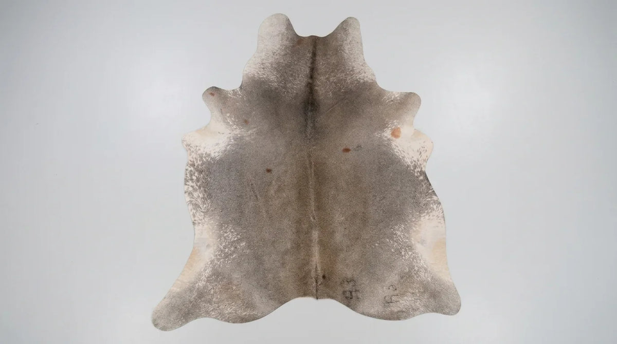 Grey cowhide rug flat lay on white background showing full hide shape