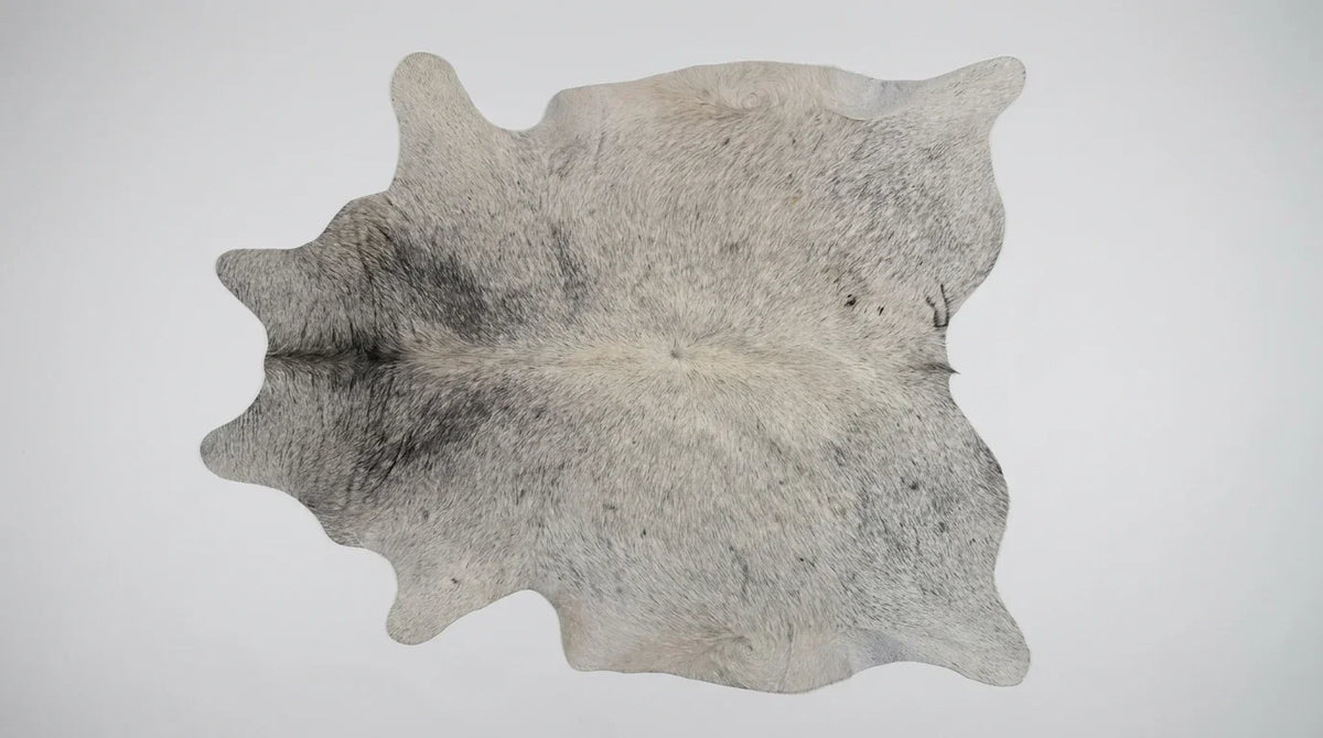 Grey cowhide rug flat lay on white background showing full hide shape