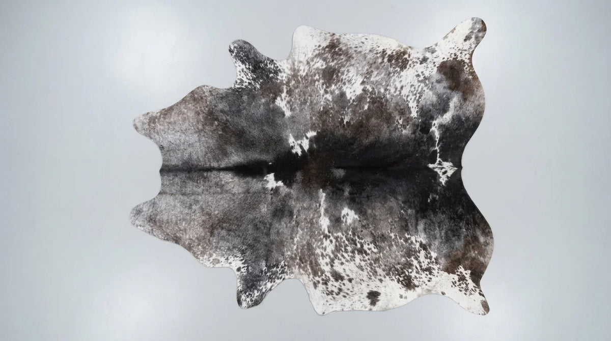 Grey cowhide rug flat lay on white background showing full hide shape