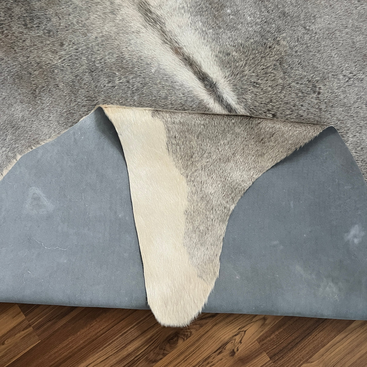 Close-up texture of Grey cowhide rug — Fine salt-and-pepper texture with darker grey patches over cream-white base