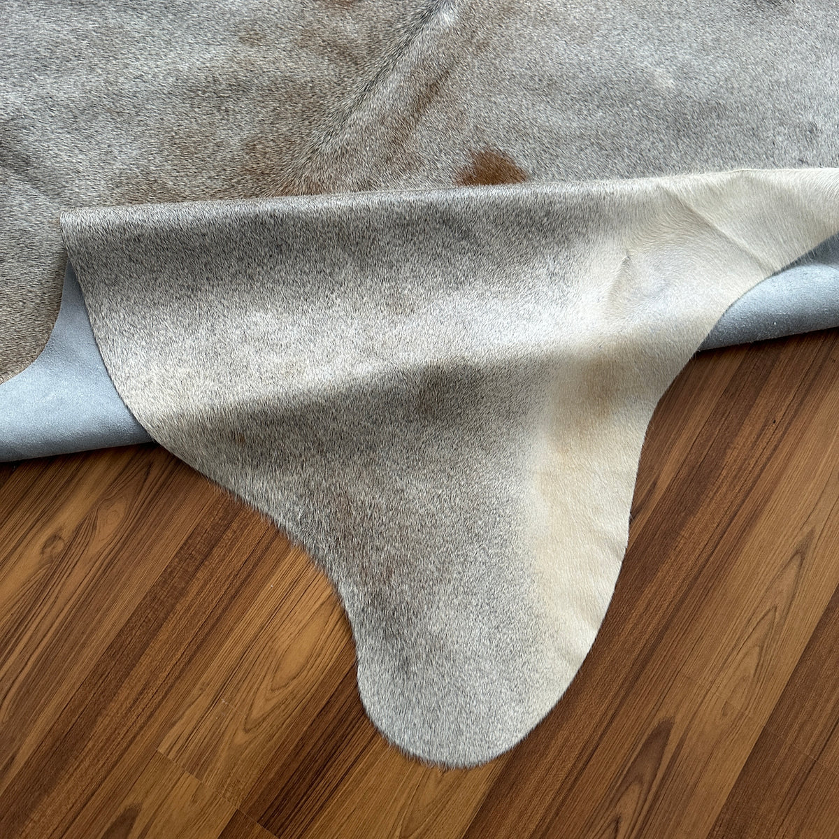 Close-up texture of Grey cowhide rug — Large irregular grey and cream patches with natural mottling and subtle tan undertones