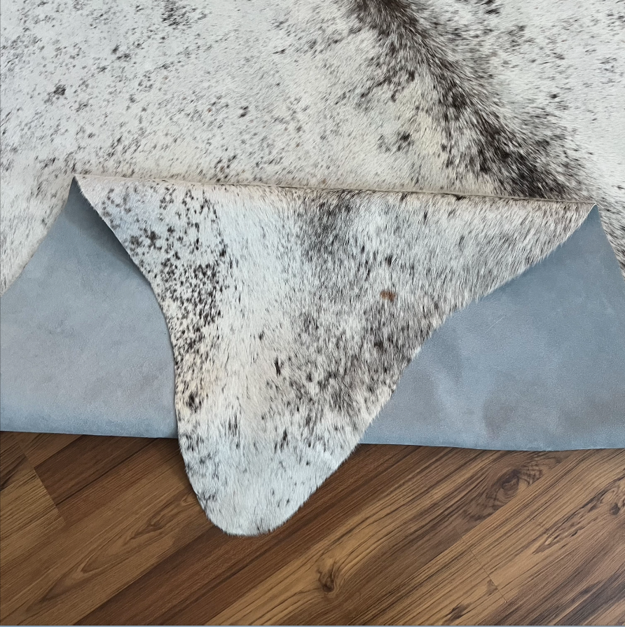 Close-up texture of Grey cowhide rug — Fine salt and pepper speckle with darker mottled patches throughout cream base