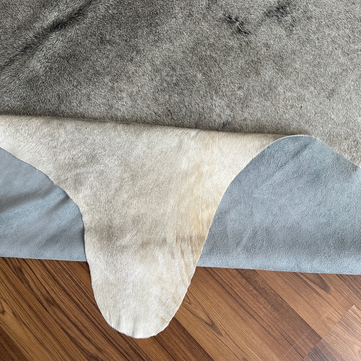 Close-up texture of Grey cowhide rug — Light grey base with subtle darker grey patches and natural markings