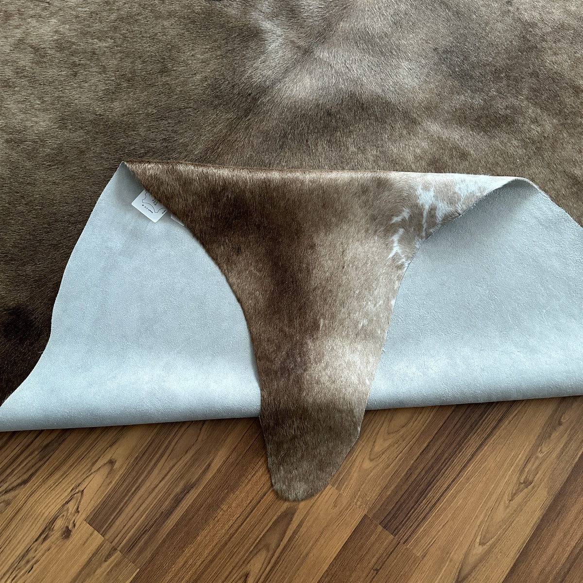 Close-up texture of Grey cowhide rug — Large irregular dark brown and charcoal patches over light grey base