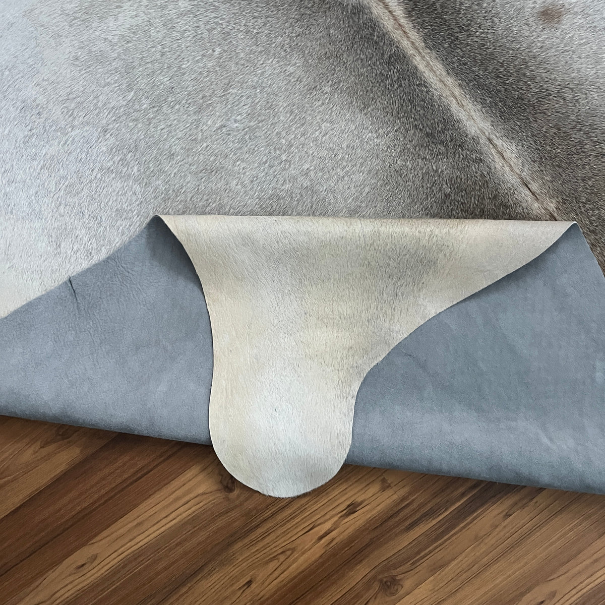 Close-up texture of Grey cowhide rug — Large irregular grey and white patches with darker grey markings over cream base