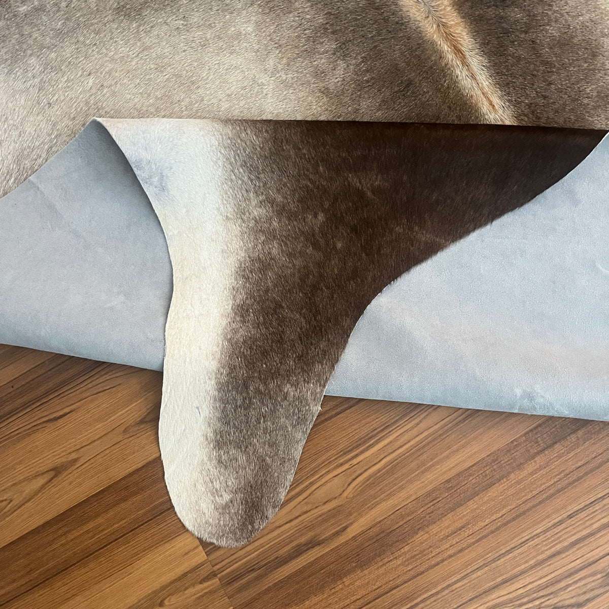 Close-up texture of Grey cowhide rug — Large irregular dark grey and charcoal patches over light grey base
