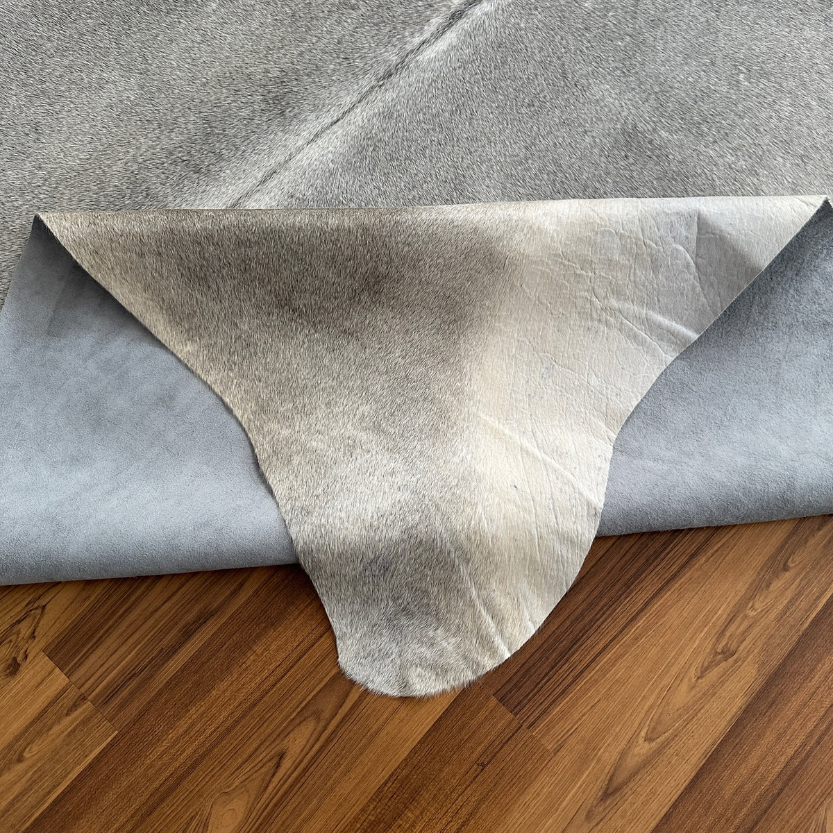 Close-up texture of Grey cowhide rug — Large irregular patches and mottled markings over light cream and grey base