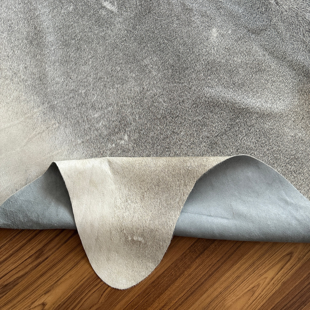 Close-up texture of Grey cowhide rug — Large irregular light grey patches with darker grey undertones over cream base