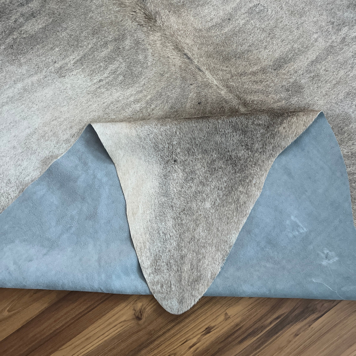 Close-up texture of Grey cowhide rug — Fine salt and pepper speckle with darker grey patches on cream base