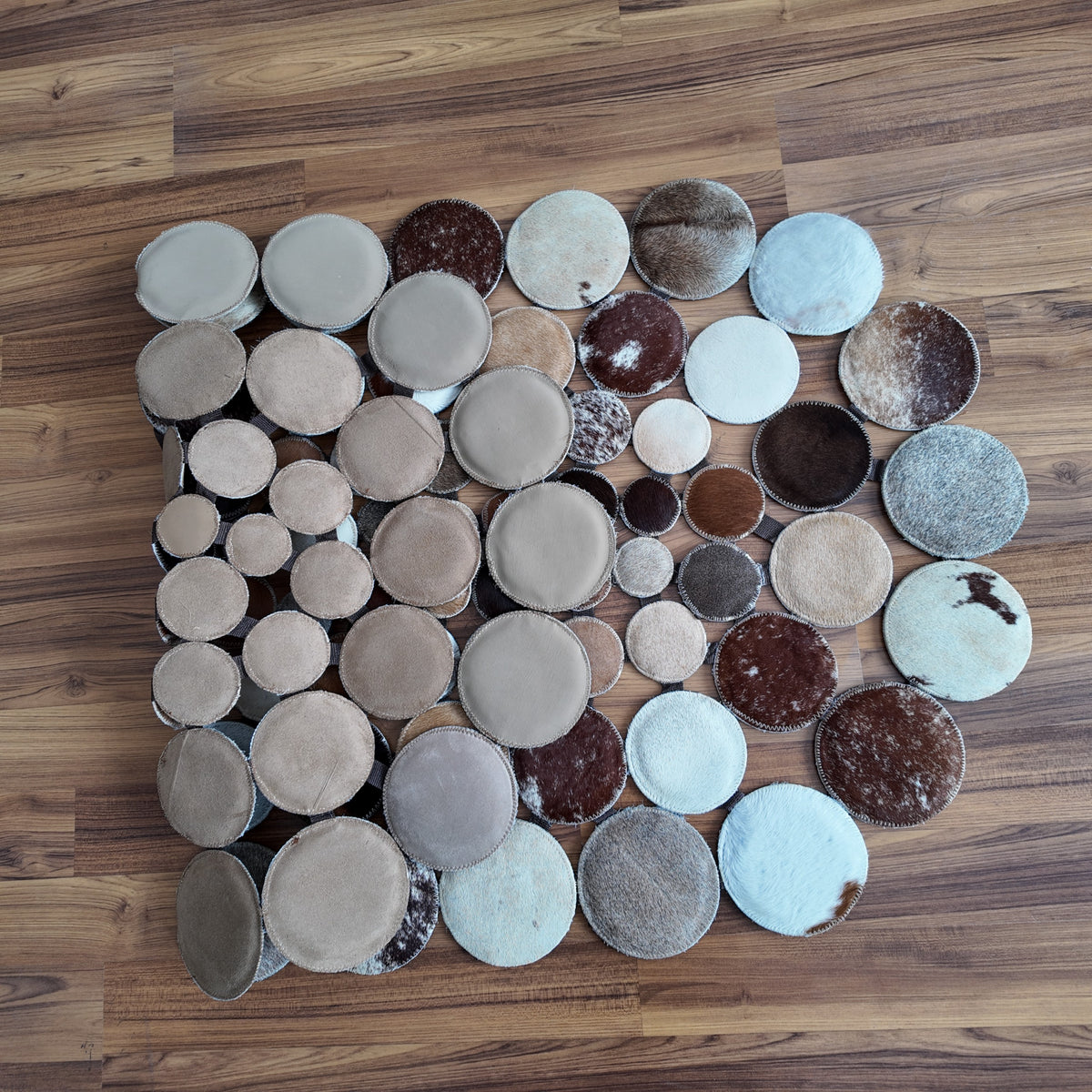 Close-up texture of Mixed Tones round patchwork cowhide rug — Assembled circular mosaic of varied hide discs in brown, cream,
