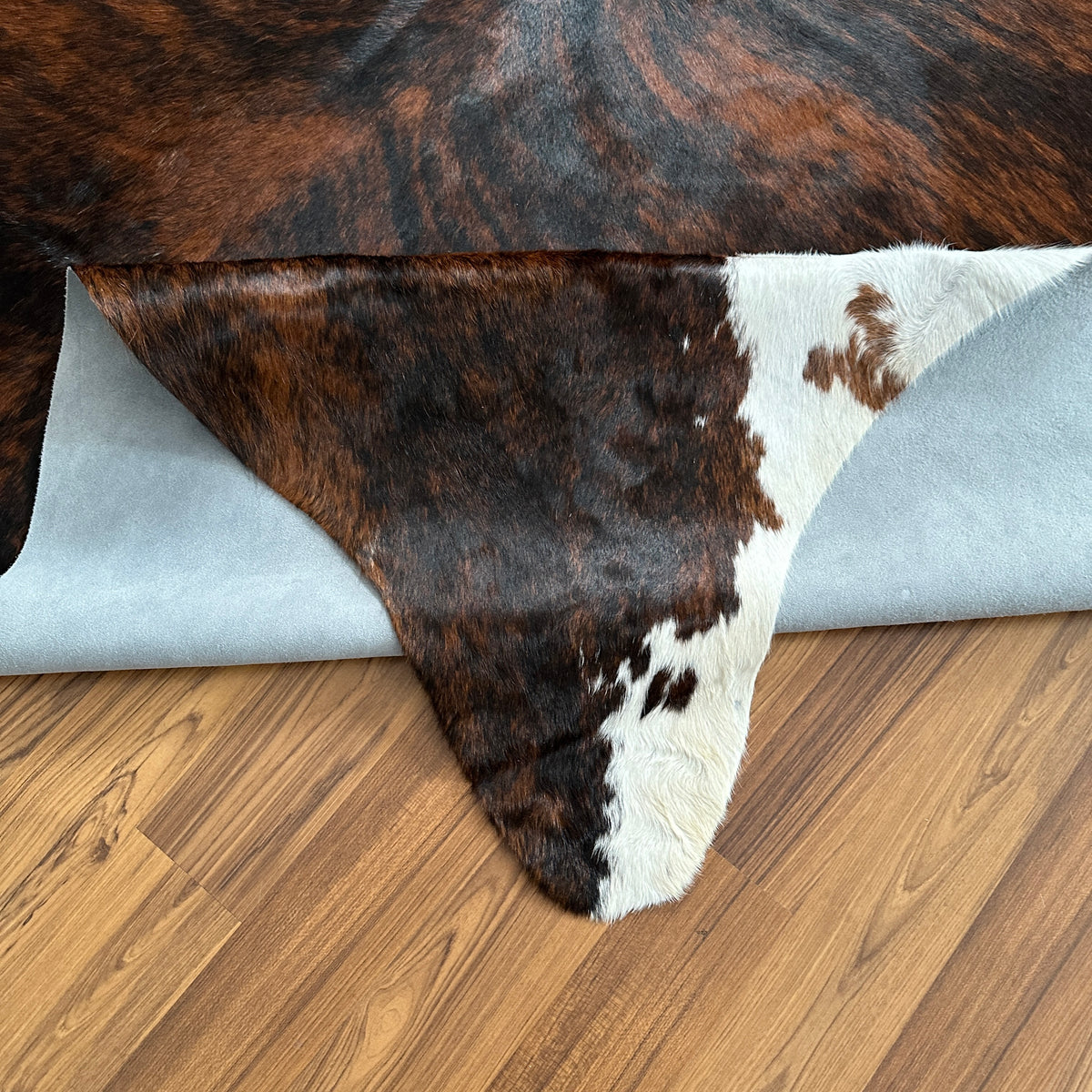 Close-up texture of Tricolor tricolor cowhide rug — Dark brown and black patches with white markings over natural hide base