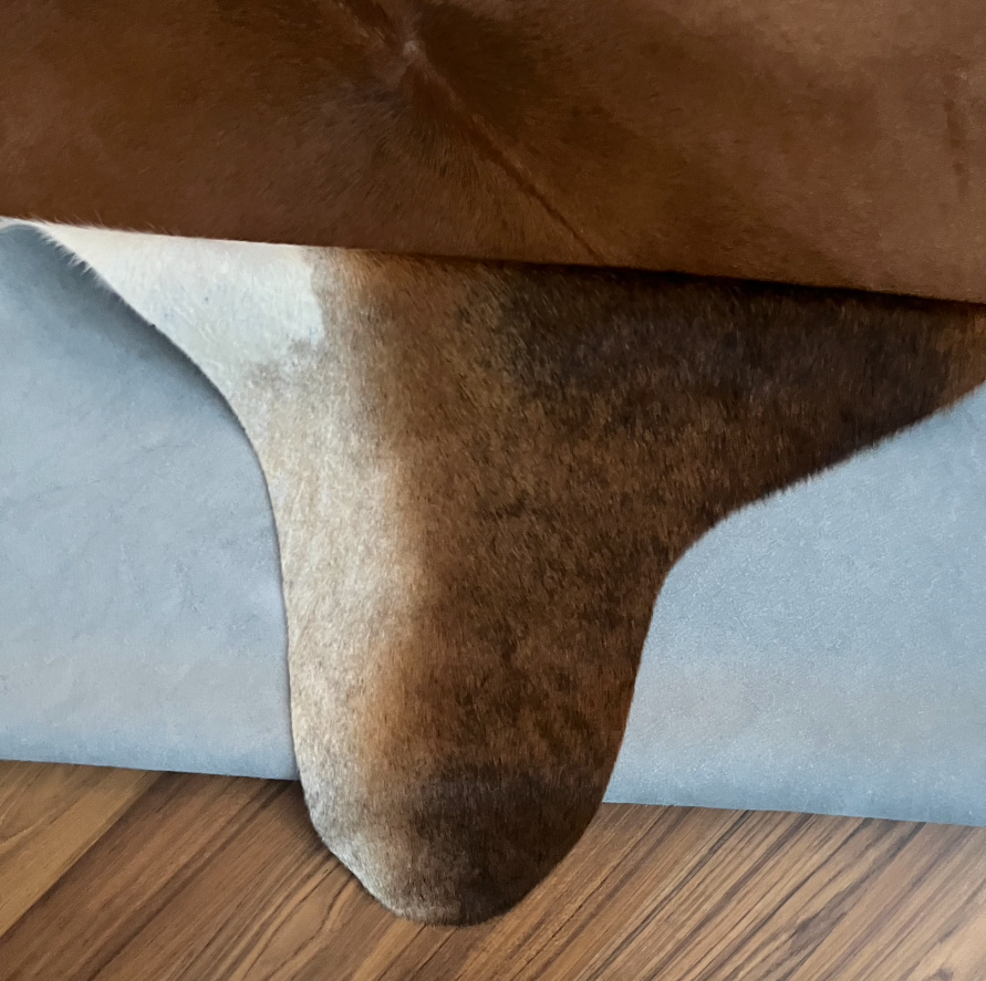 Close-up texture of Tricolor tricolor cowhide rug — Brown, black, and white irregular patches with natural hide markings
