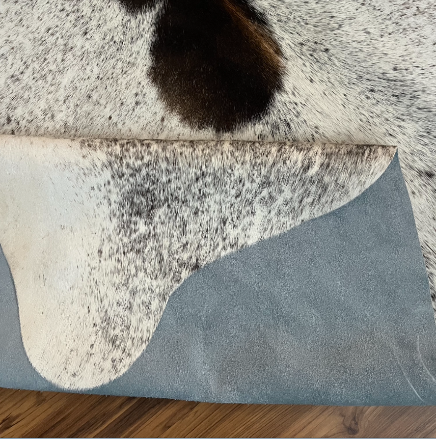 Close-up texture of Tricolor tricolor cowhide rug — Large dark brown and black patches on cream and white base with scattered