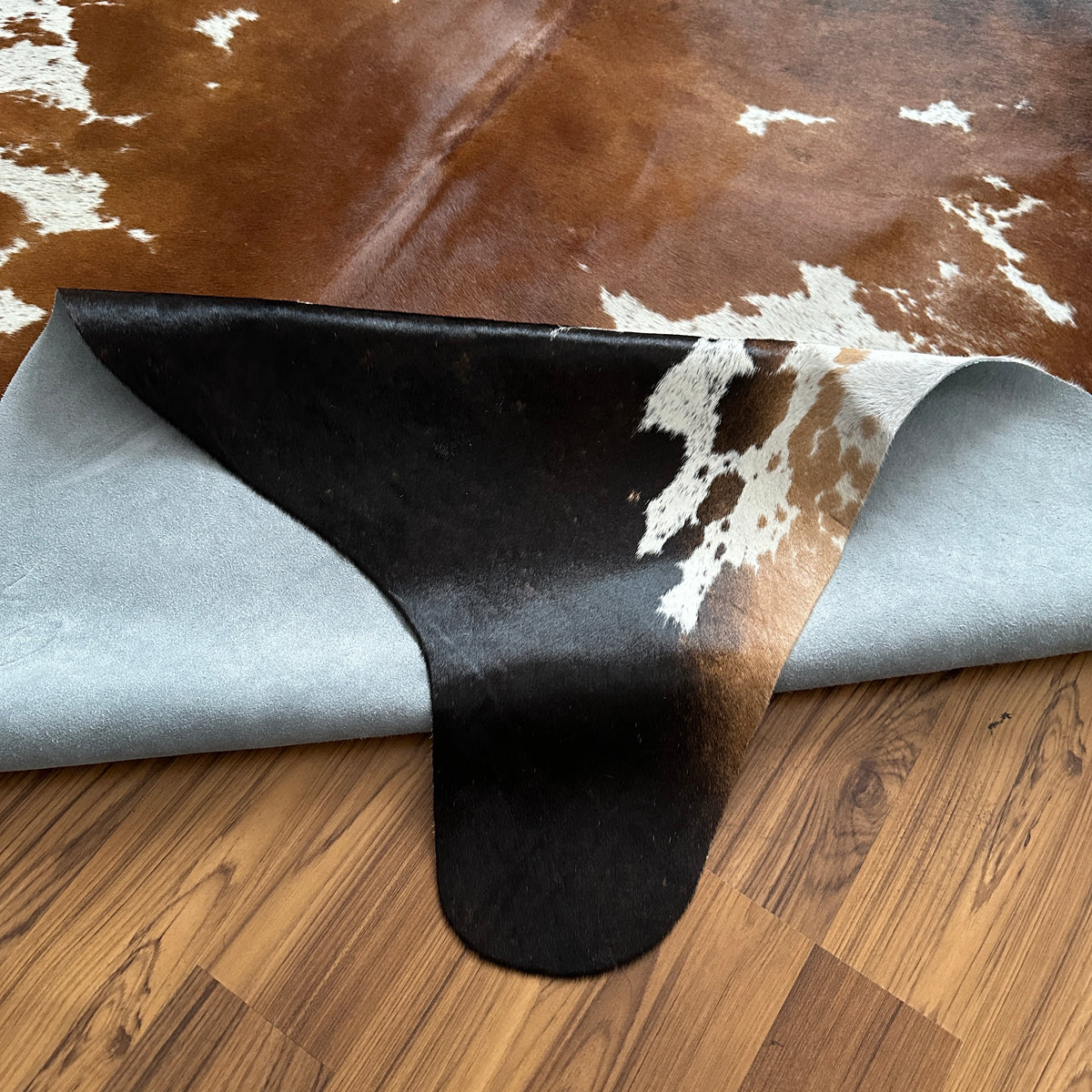 Close-up texture of Tricolor tricolor cowhide rug — Large irregular brown and black patches with cream and white undertones a