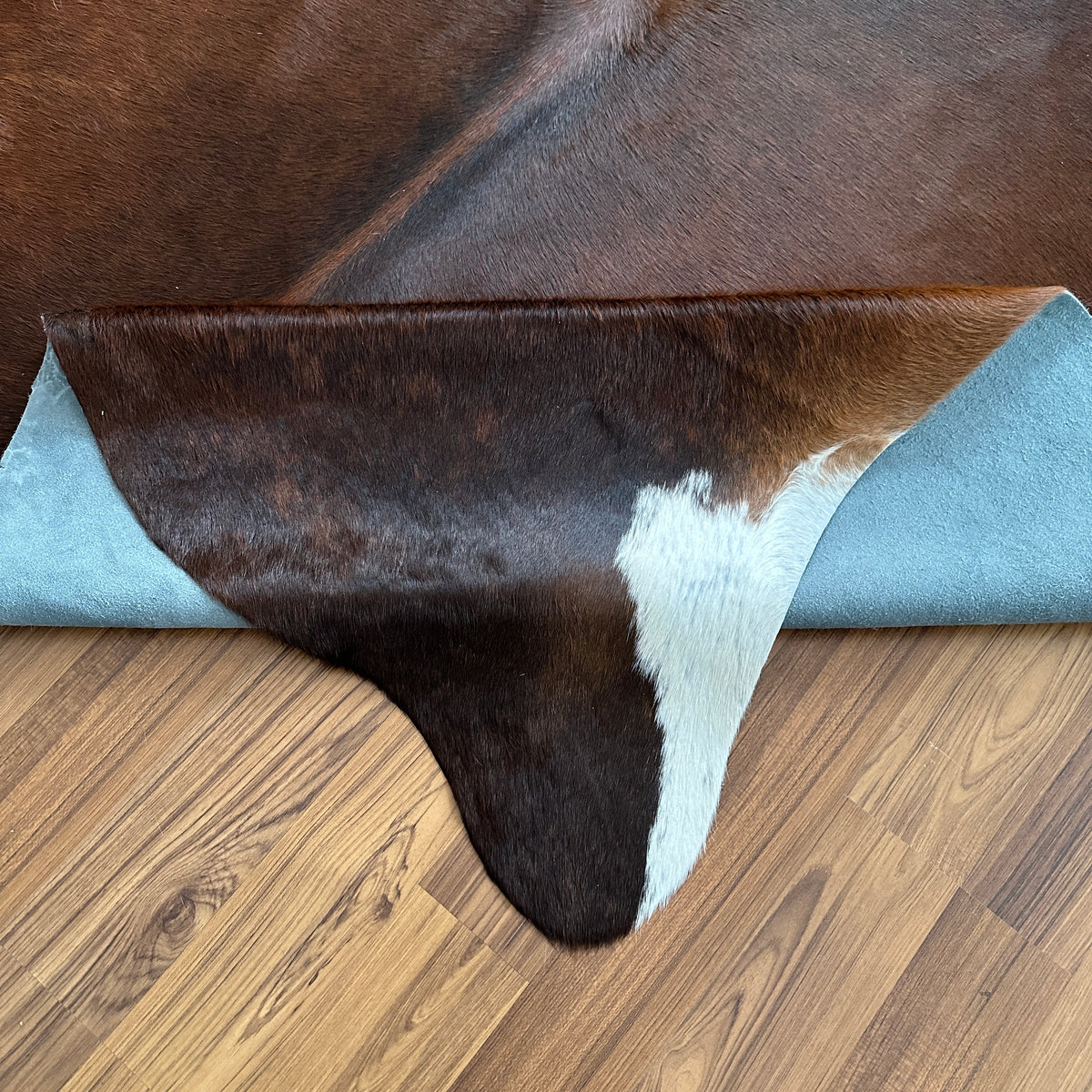 Close-up texture of Tricolor tricolor cowhide rug — Large irregular dark brown and black patches with cream and white accents